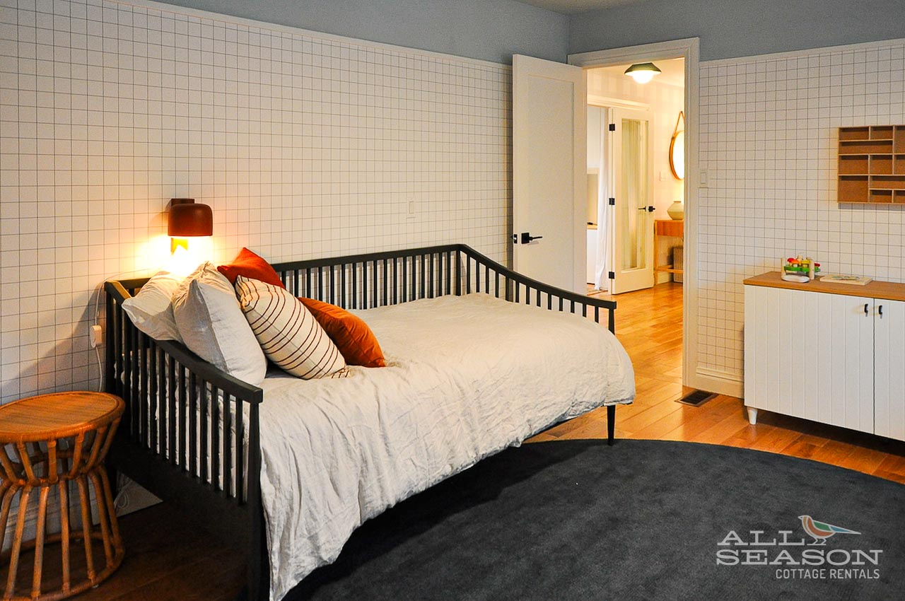 Relax in this bright bedroom with stylish grid wallpaper, cozy bedding, and warm lighting that creates your perfect retreat.