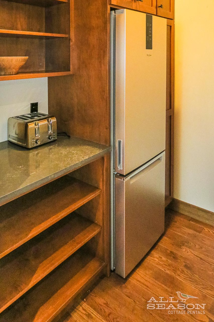 Your fully equipped kitchen features sleek stainless steel appliances and warm wood cabinetry, perfect for preparing meals during your stay.