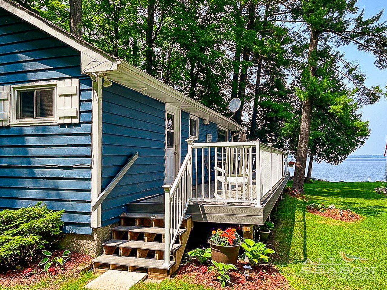 Charming blue lakefront cottage with welcoming deck where you can sip morning coffee while enjoying stunning water views.