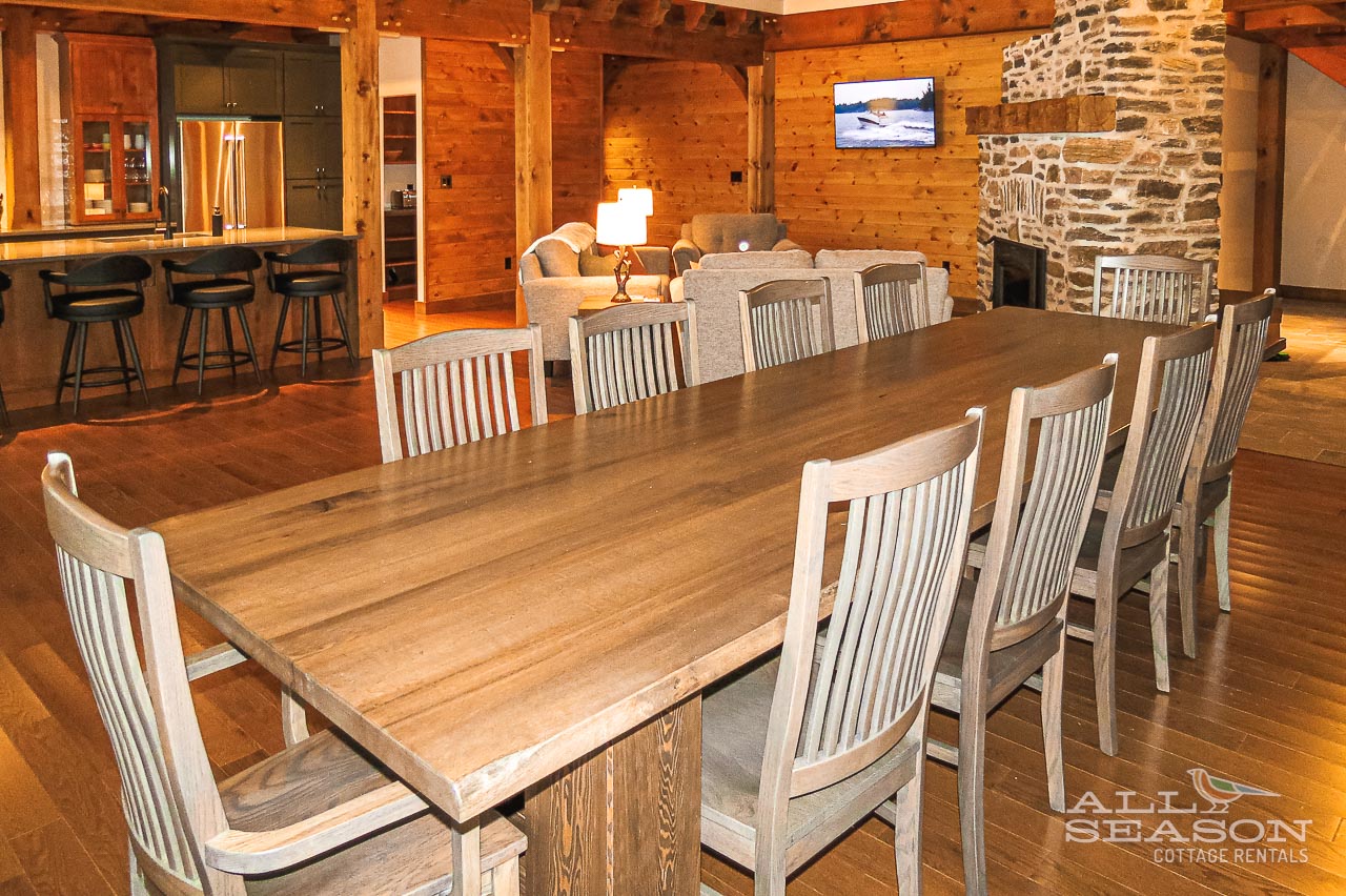 Gather your group around this handcrafted dining table where warm wood beams and stone fireplace create the perfect backdrop for memorable meals together.