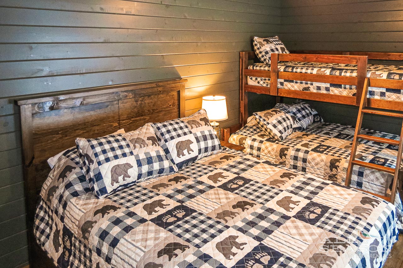 Cozy rustic bedroom with charming bear-themed bedding and bunk beds, perfect for your mountain getaway adventure.