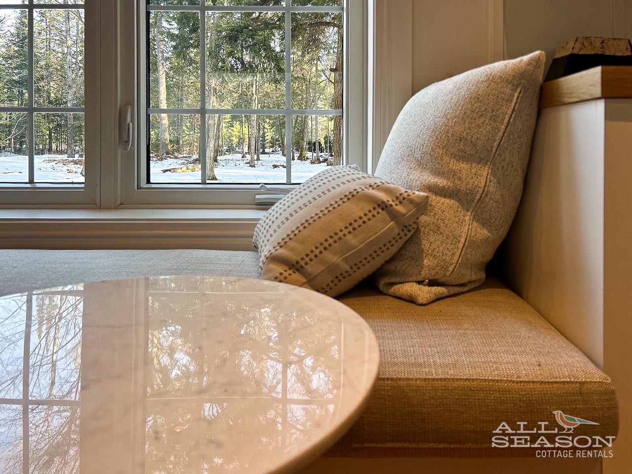 Sink into your cozy reading nook with plush cushions and pillows, where snowy forest views create the perfect winter retreat backdrop.