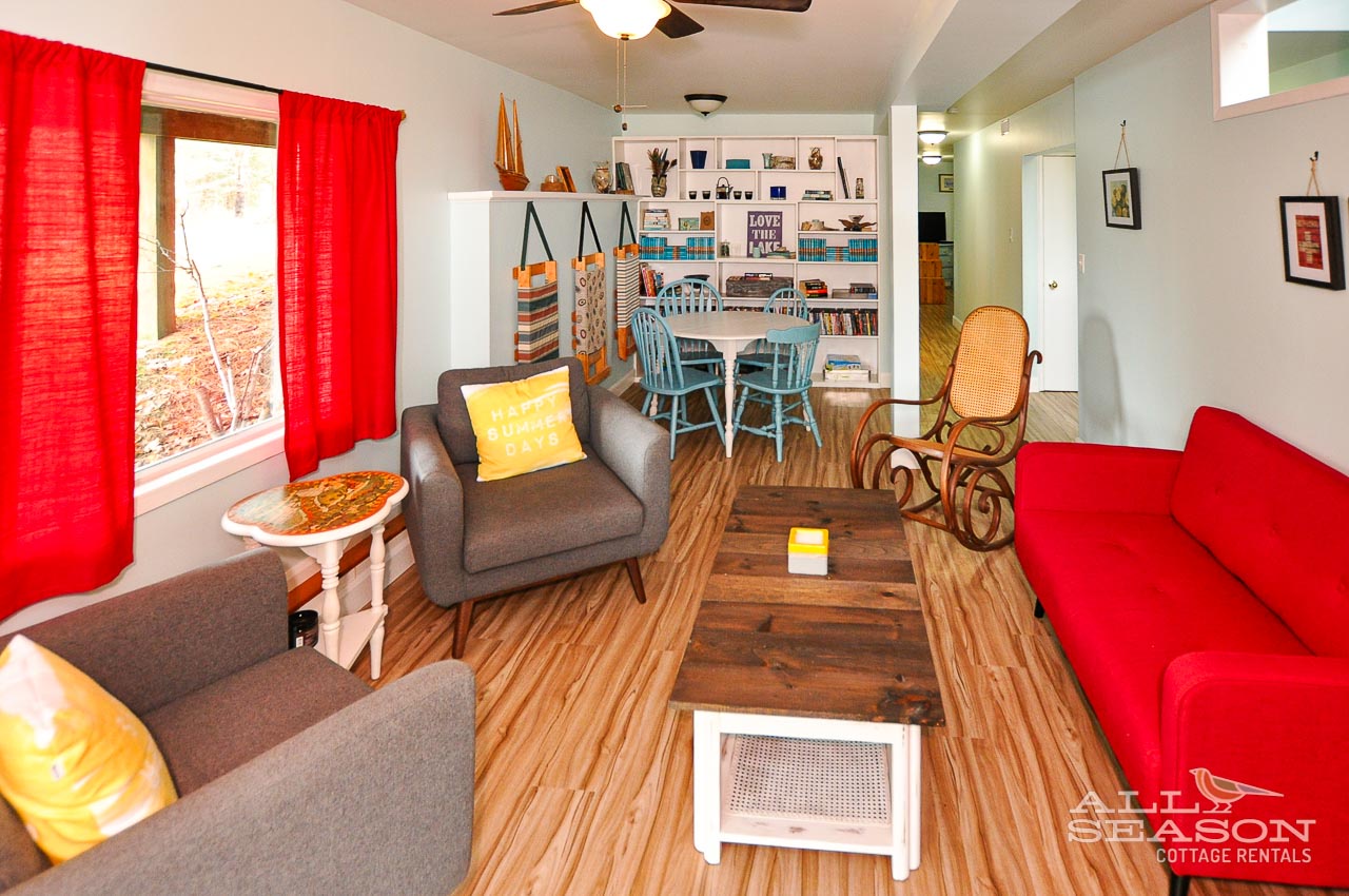 Relax in your bright living space with colorful pops of red and yellow, where comfortable seating surrounds polished wood floors.