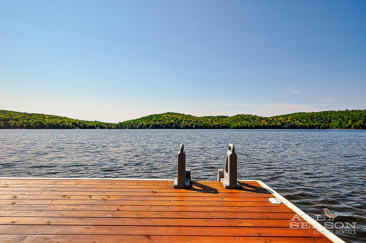 Peaceful lakefront dock surrounded by rolling hills and pristine waters - perfect for morning coffee or evening relaxation.