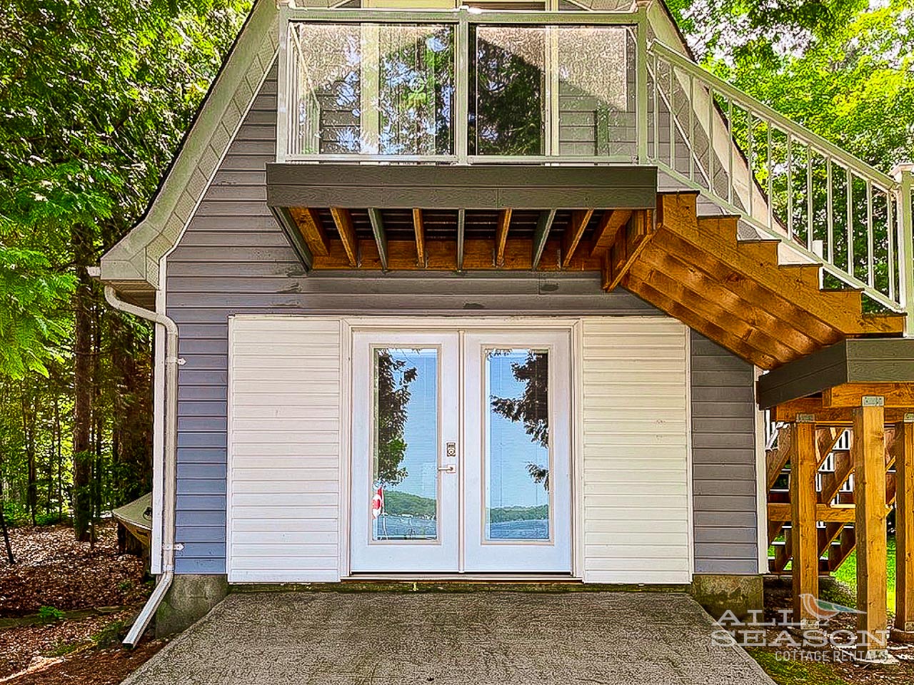 Charming lakeside cabin entrance with modern glass doors reflecting the water views you'll wake up to each morning.