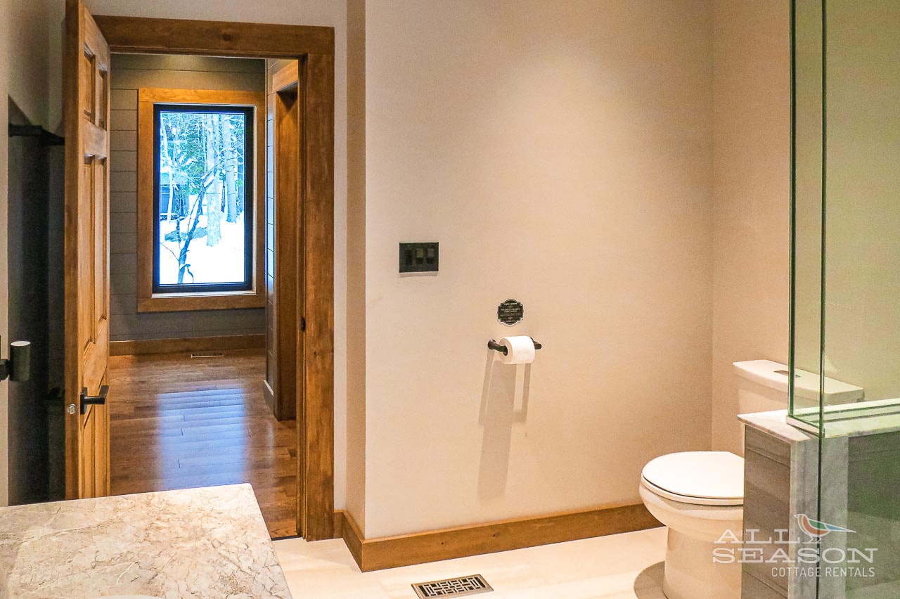 Enjoy your private spa-like bathroom with elegant finishes and winter forest views through the window.