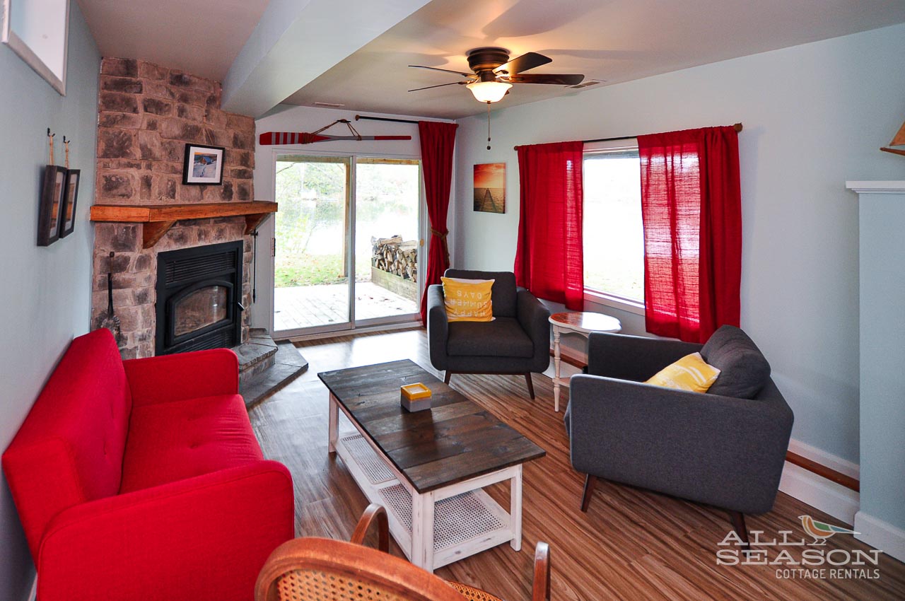 Cozy up in your inviting living room with warm brick fireplace, comfy seating, and cheerful red accents that create the perfect atmosphere for relaxation.