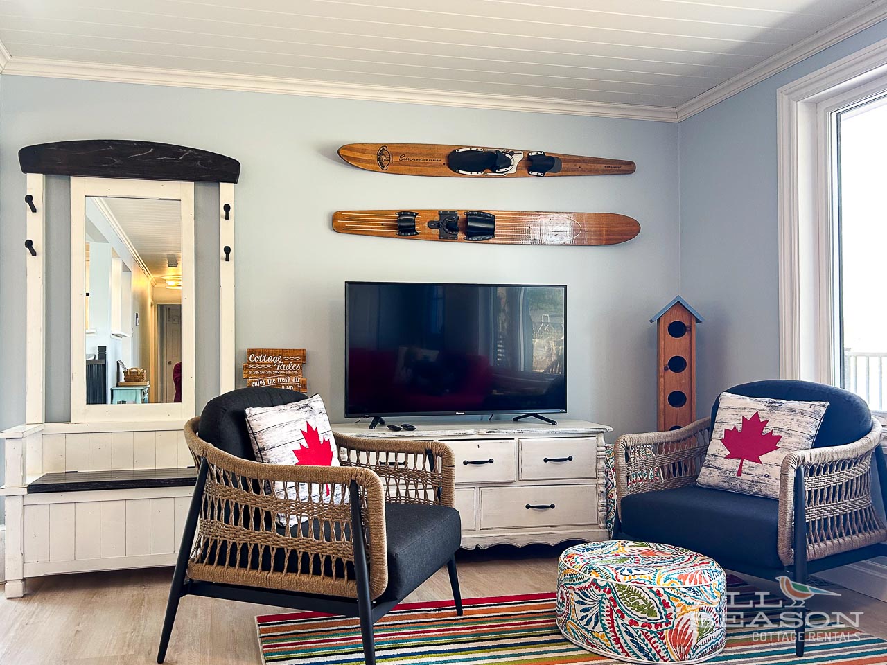 Settle into this charming living room where vintage water skis and cozy wicker chairs create the perfect cottage retreat for your lakeside getaway.