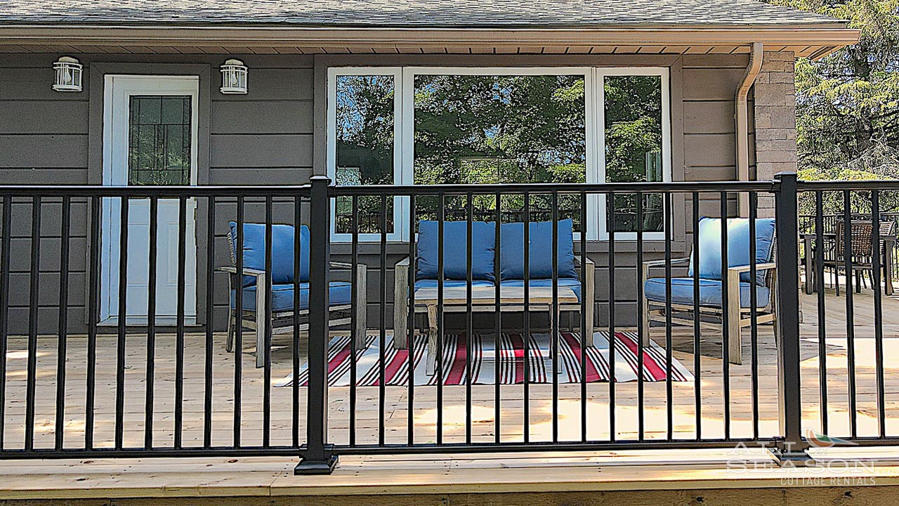 Relax on your private deck with comfortable blue seating and scenic tree views through large windows.
