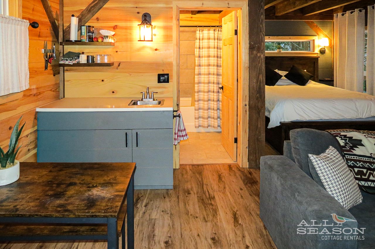 Your cozy cabin retreat features warm wood beams, modern kitchenette, and comfortable seating—perfect for unwinding after mountain adventures.