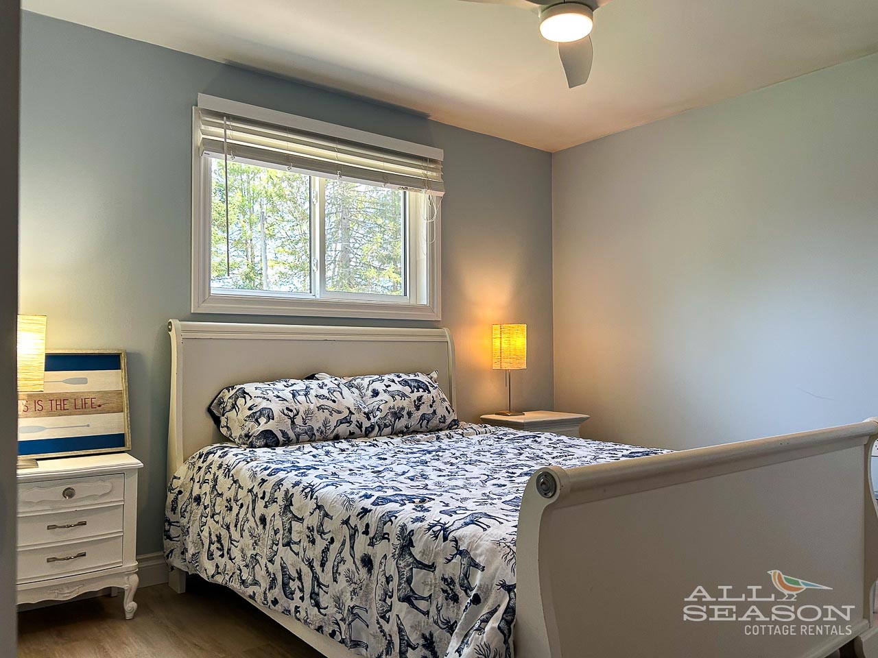 Sink into your cozy bedroom sanctuary with soft gray walls, warm bedside lighting, and a charming floral-patterned bed that promises restful nights.