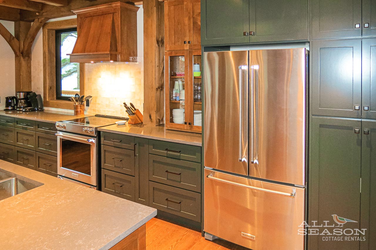 Your gourmet kitchen features gleaming stainless steel appliances, rich wood cabinetry, and warm lighting that creates the perfect cooking atmosphere.