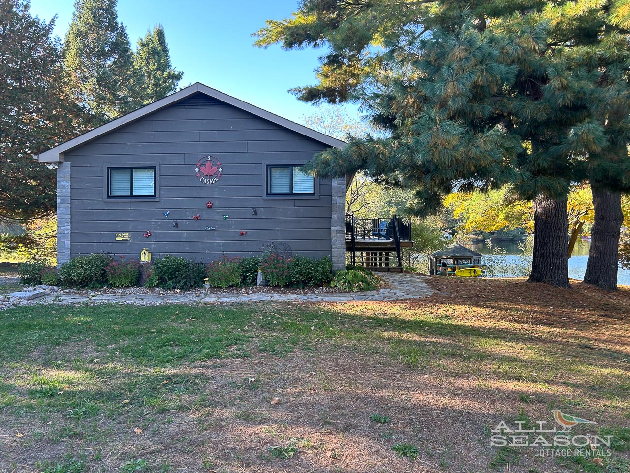 Charming lakeside cottage with autumn foliage and peaceful waterfront setting.