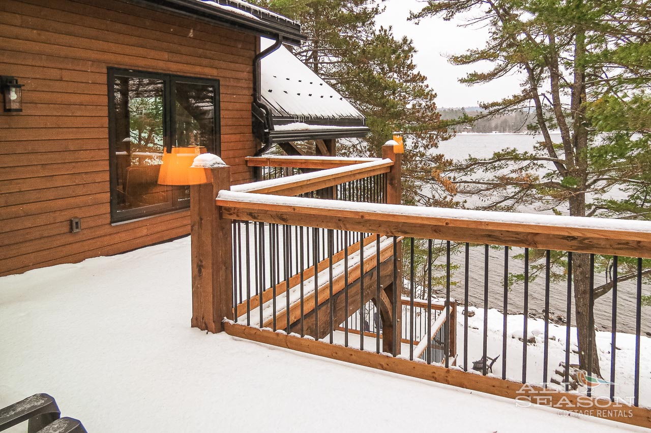 Your private balcony overlooks serene winter waters through towering pines, creating the perfect retreat for morning coffee.