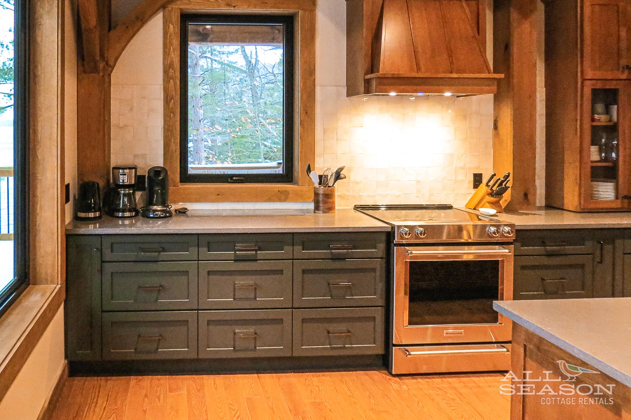 Cook in your spacious kitchen with stainless appliances, rich wood beams, and natural light streaming through forest views.