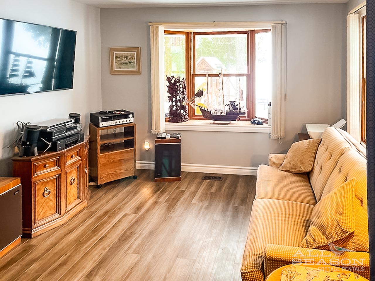 Sink into your cozy living room with warm hardwood floors, entertainment center, and sunny windows framing garden views.
