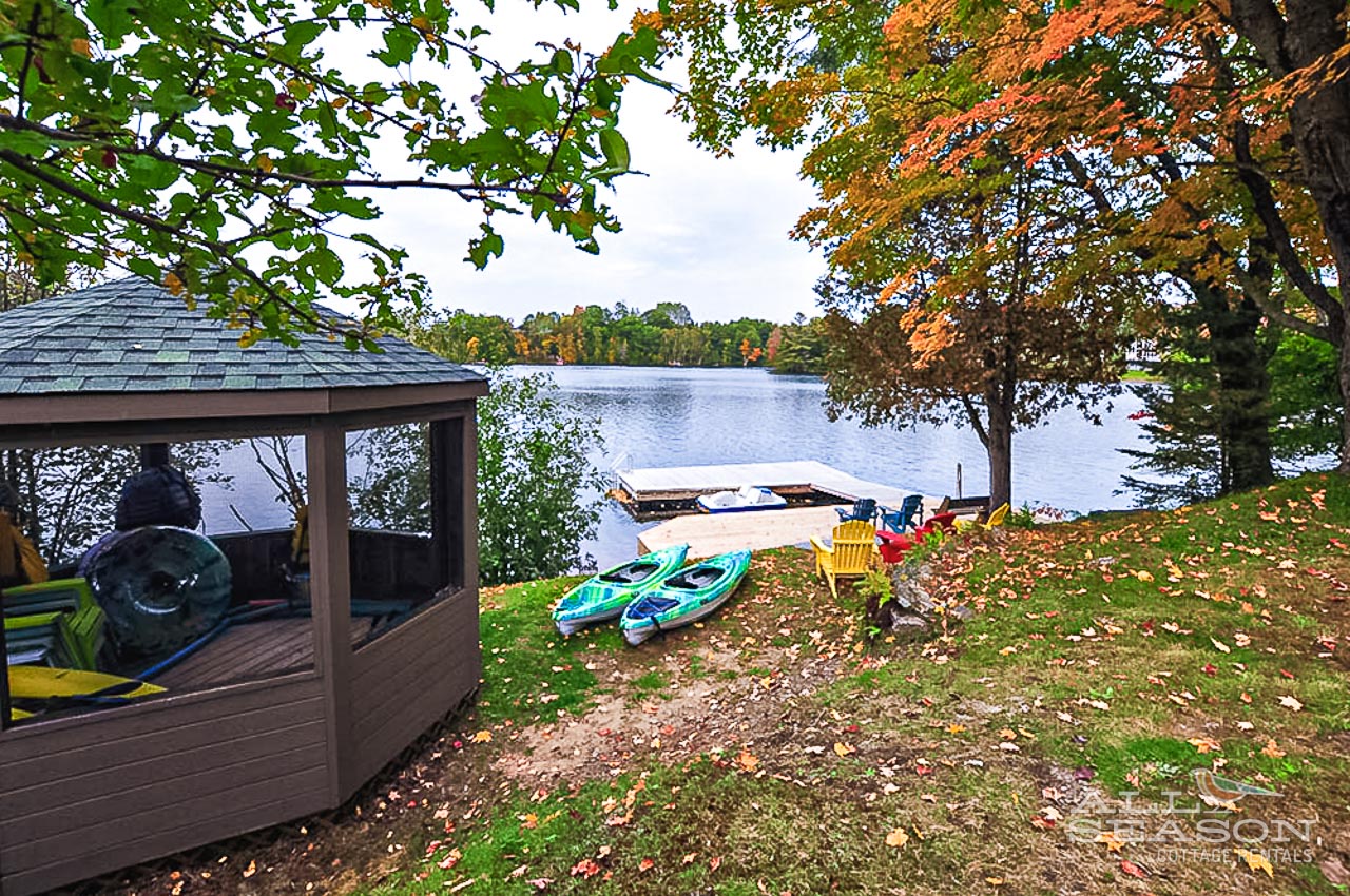 Lakefront retreat with kayaks and dock amid stunning autumn foliage and peaceful waters.