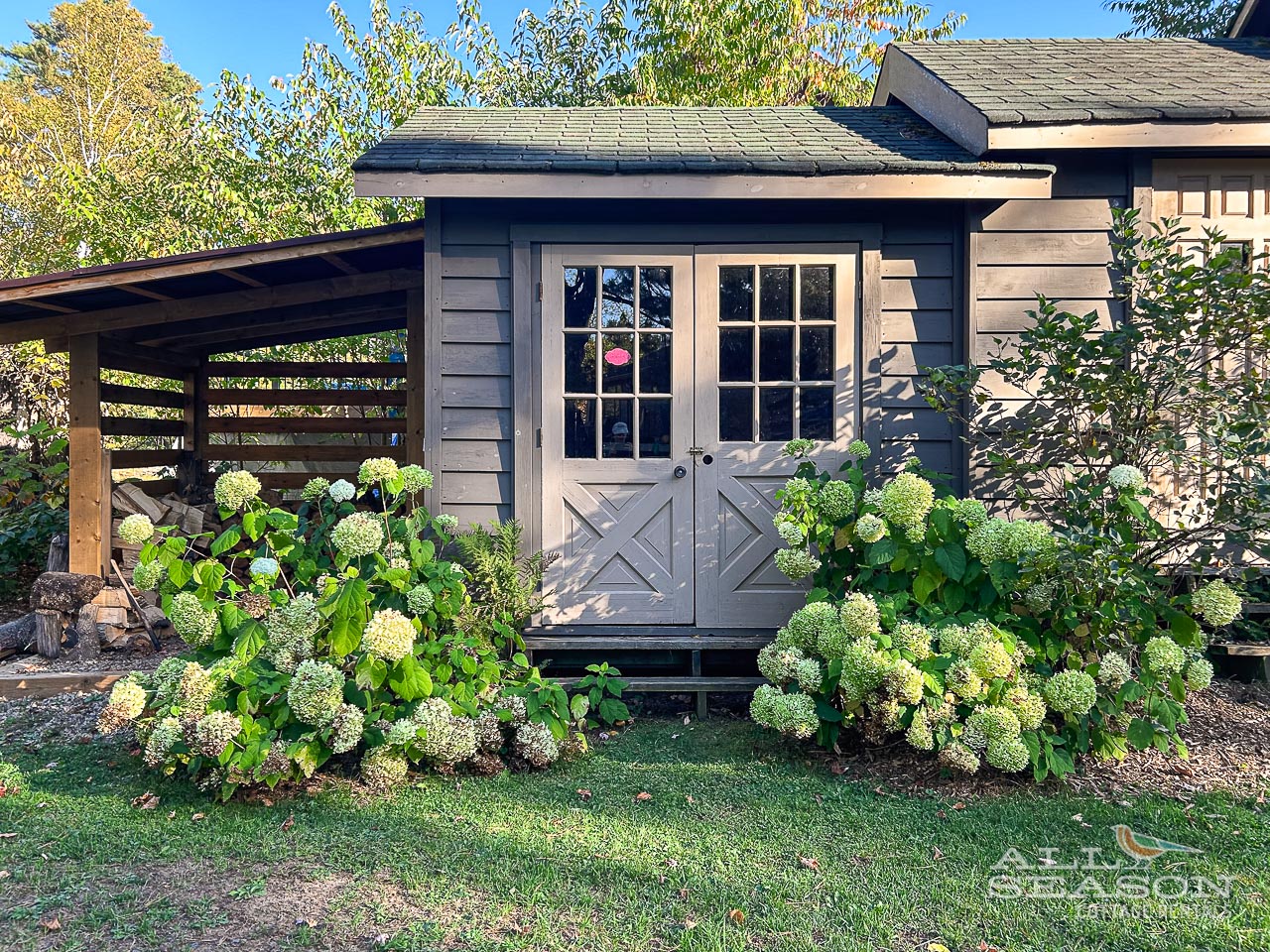 Charming cottage exterior with beautiful hydrangea gardens and covered outdoor space for relaxing.