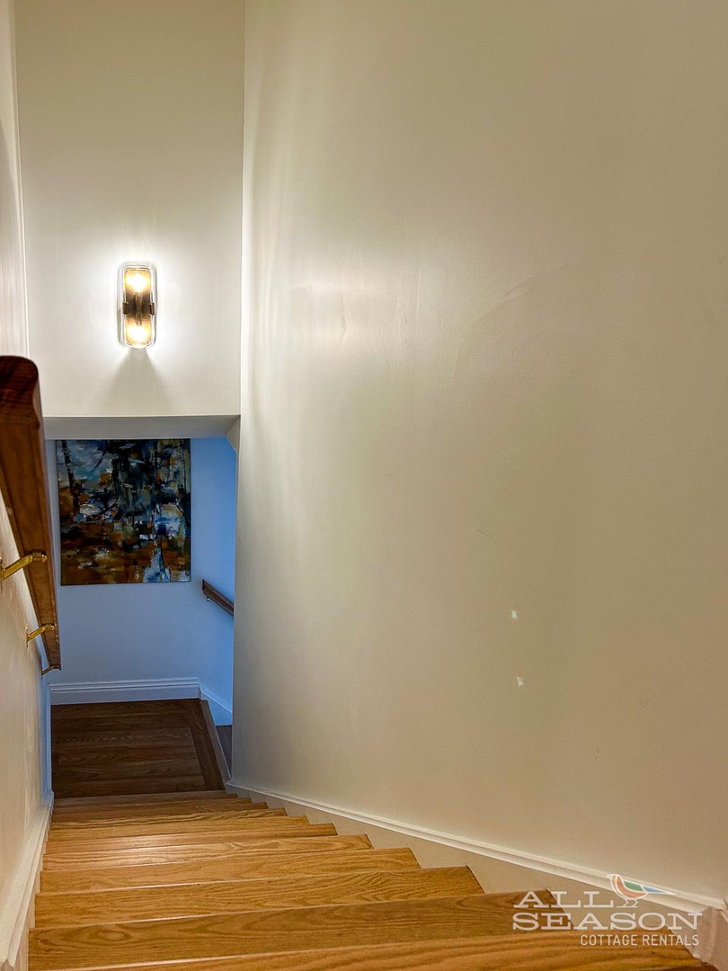 Warm lighting guides your way down beautiful hardwood stairs to the welcoming lower level of your retreat.