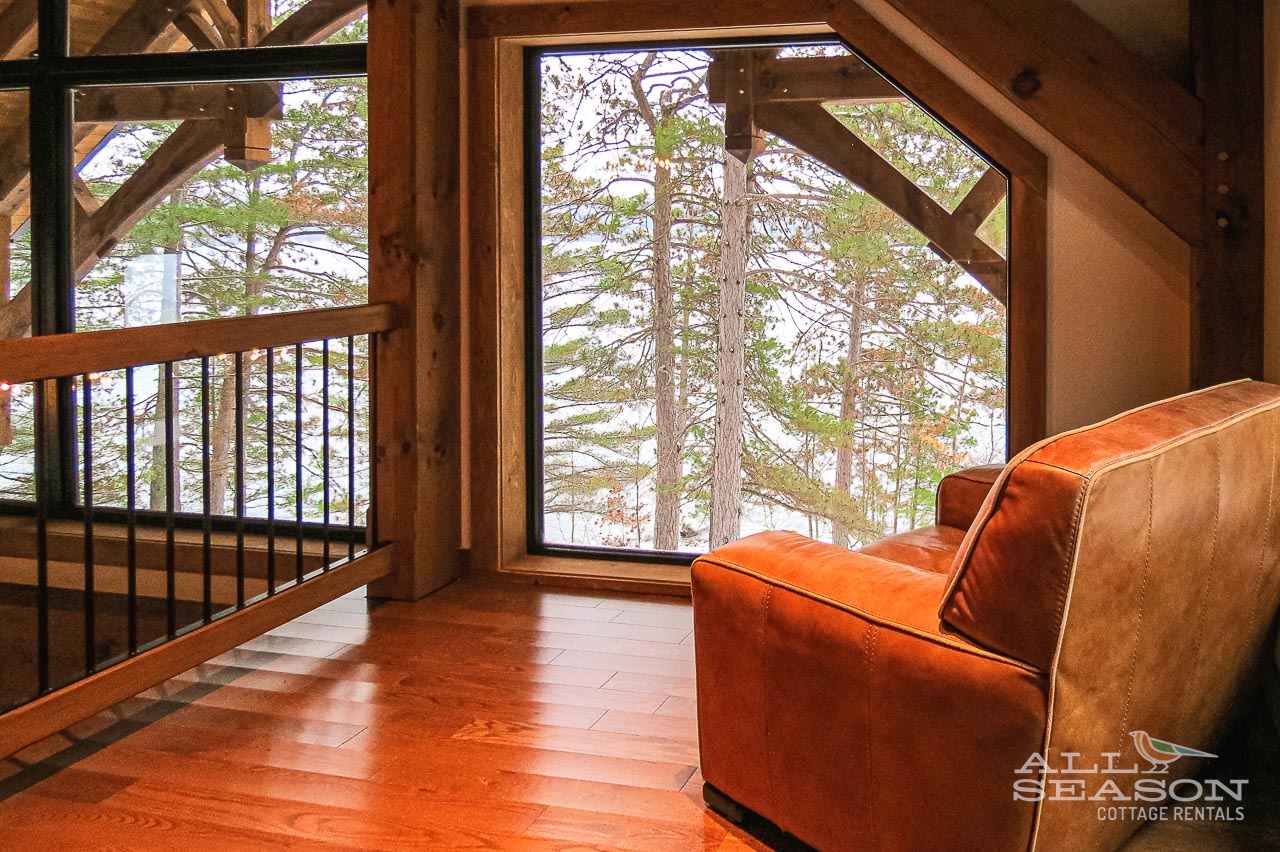 Sink into this cozy leather chair and gaze through the expansive windows at the serene forest views outside your retreat.