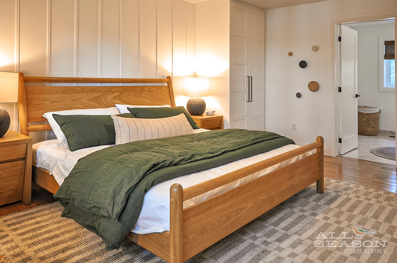 Sink into this cozy bedroom with warm wood furnishings and forest-green linens for your perfect restful retreat.