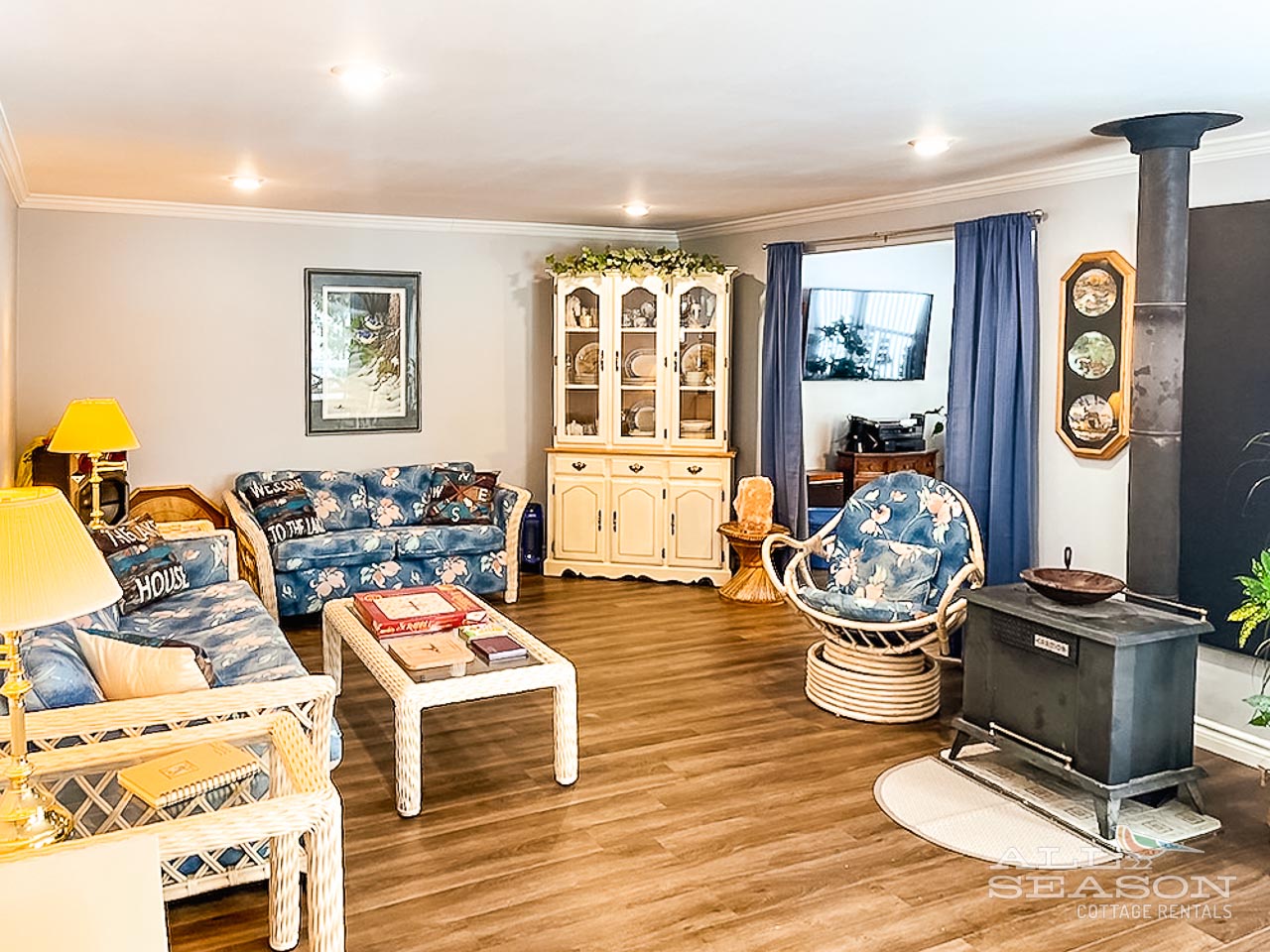 Sink into comfortable wicker seating by your cozy wood-burning fireplace, where warm lighting and charming cottage decor create the perfect retreat.