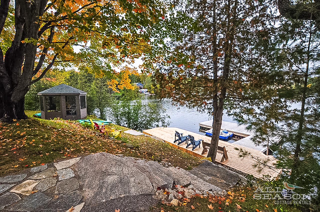 Scenic lakefront setting surrounded by vibrant autumn foliage, featuring a private dock and charming gazebo for peaceful waterfront moments.