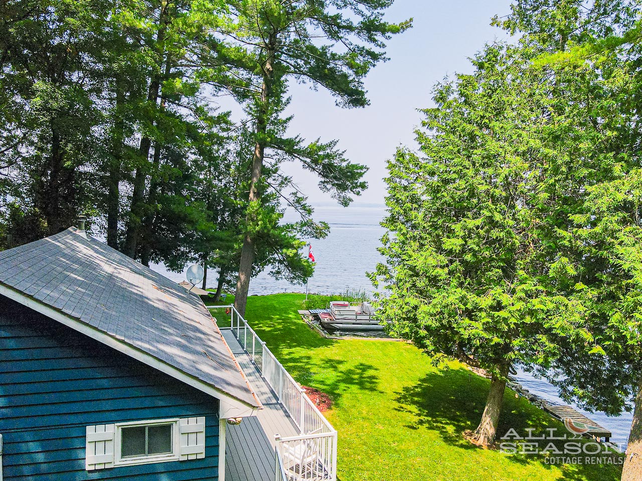 Waterfront cottage with pristine lawn stretching to the lake's edge, surrounded by mature trees for perfect lakeside tranquility.