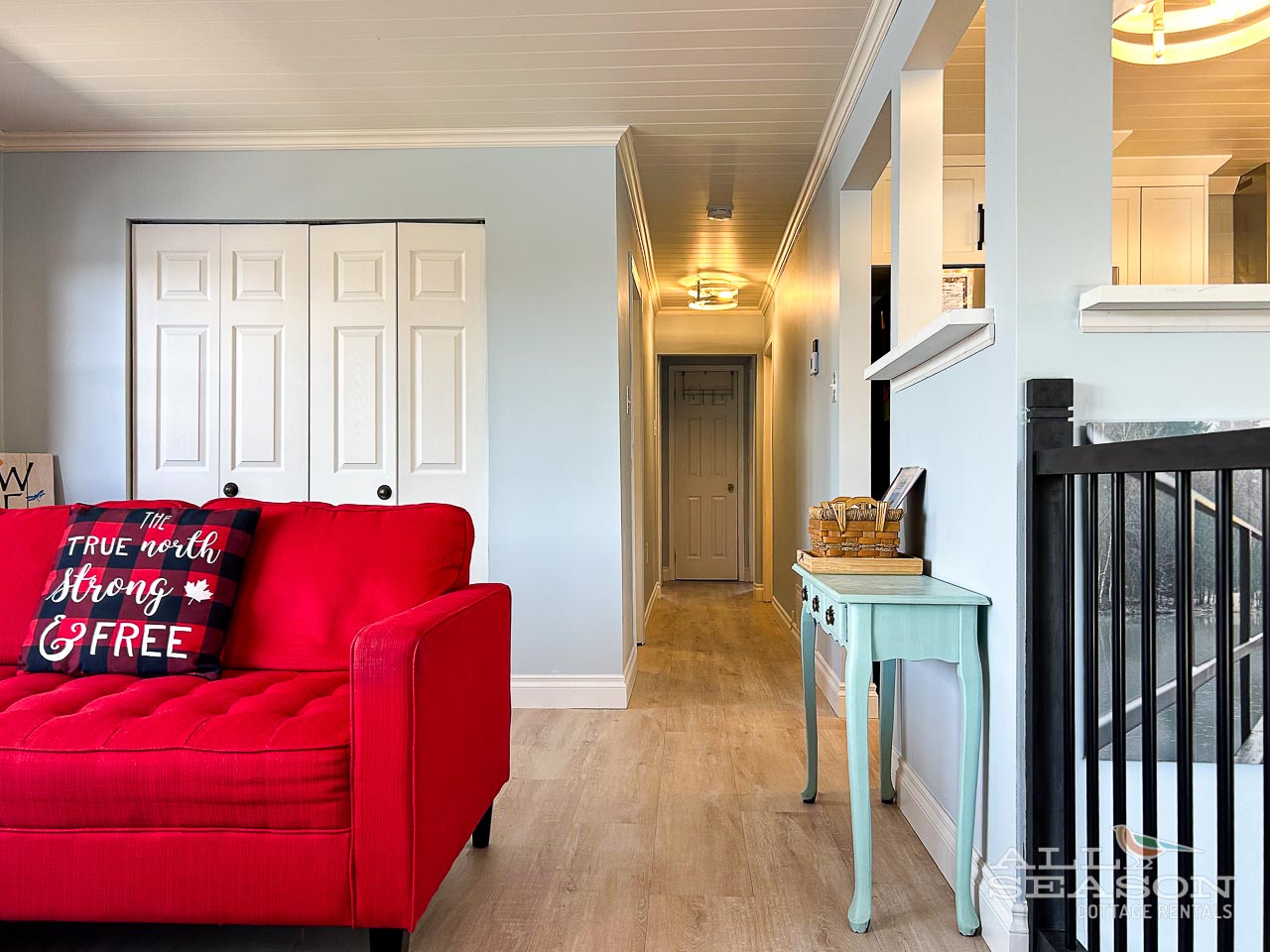 Cozy up on your vibrant red sofa in this bright, welcoming living space with charming coastal details and warm wood ceilings.
