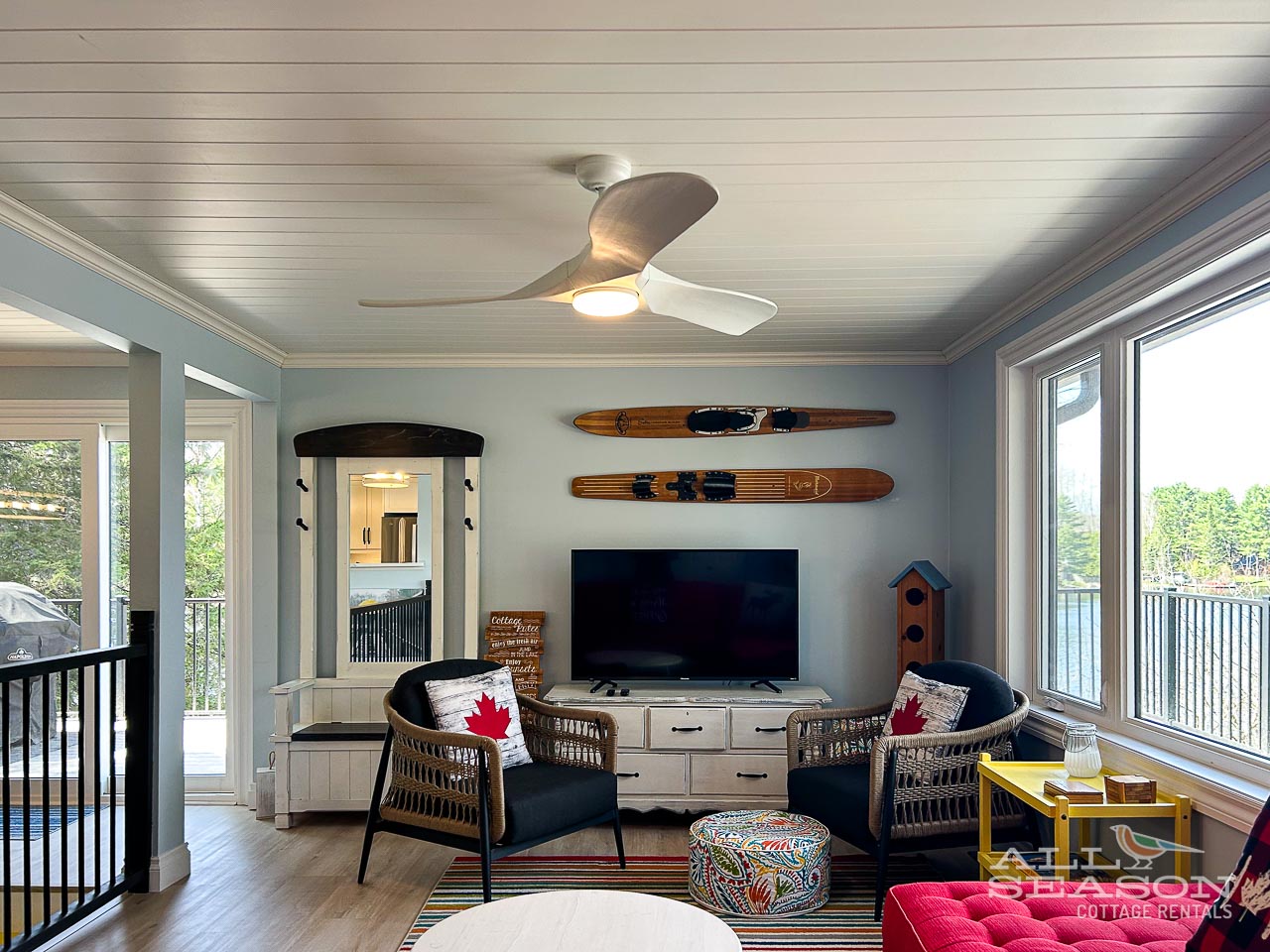 Relax in your bright living room with vintage water skis, a ceiling fan, and windows overlooking the lake.