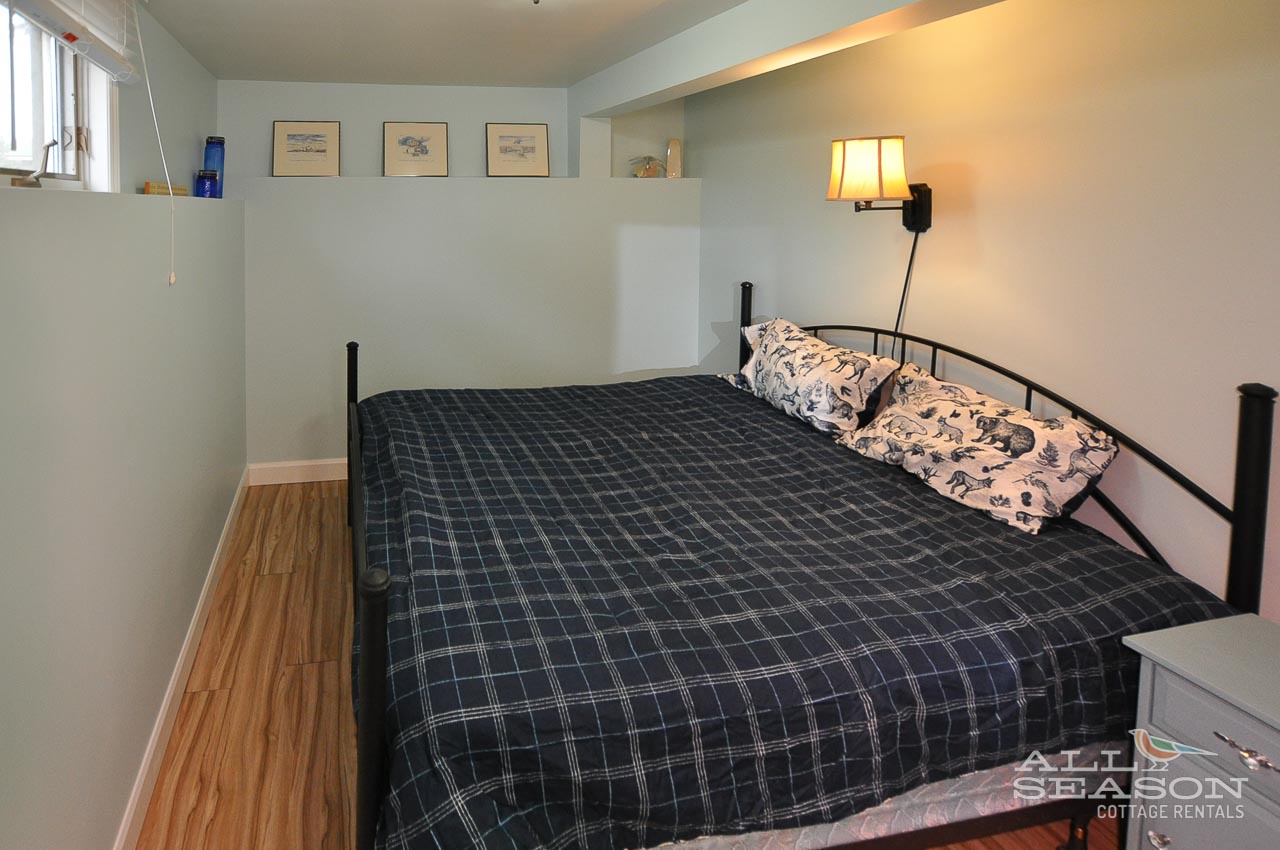 Rest peacefully in your cozy bedroom with warm wood floors, bedside lighting, and thoughtful touches like framed art creating a welcoming retreat.