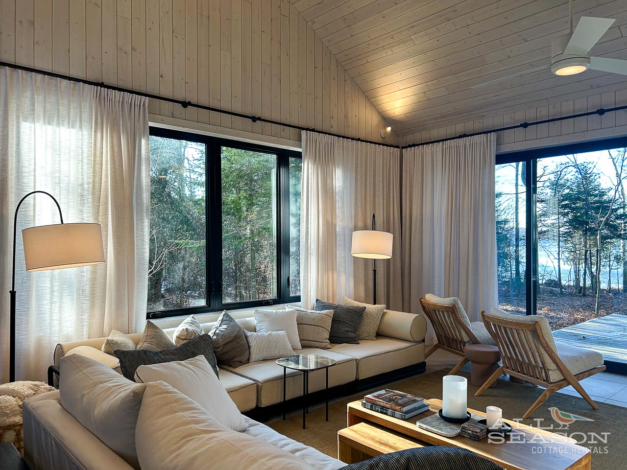 Unwind in your stylish living room with floor-to-ceiling windows framing forest views, plush seating, and warm wood accents.