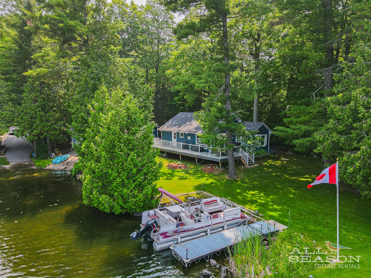 Elevated lakefront cottage with private dock and boat access, surrounded by lush forest canopy.