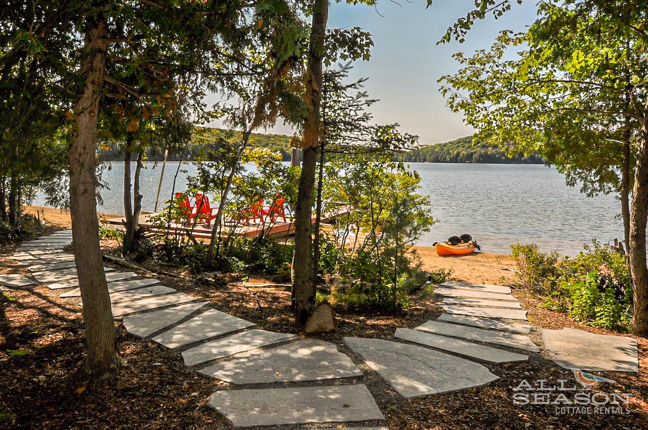 Shaded stone pathways lead through mature trees to your private lakefront beach, where kayaks await your next adventure.