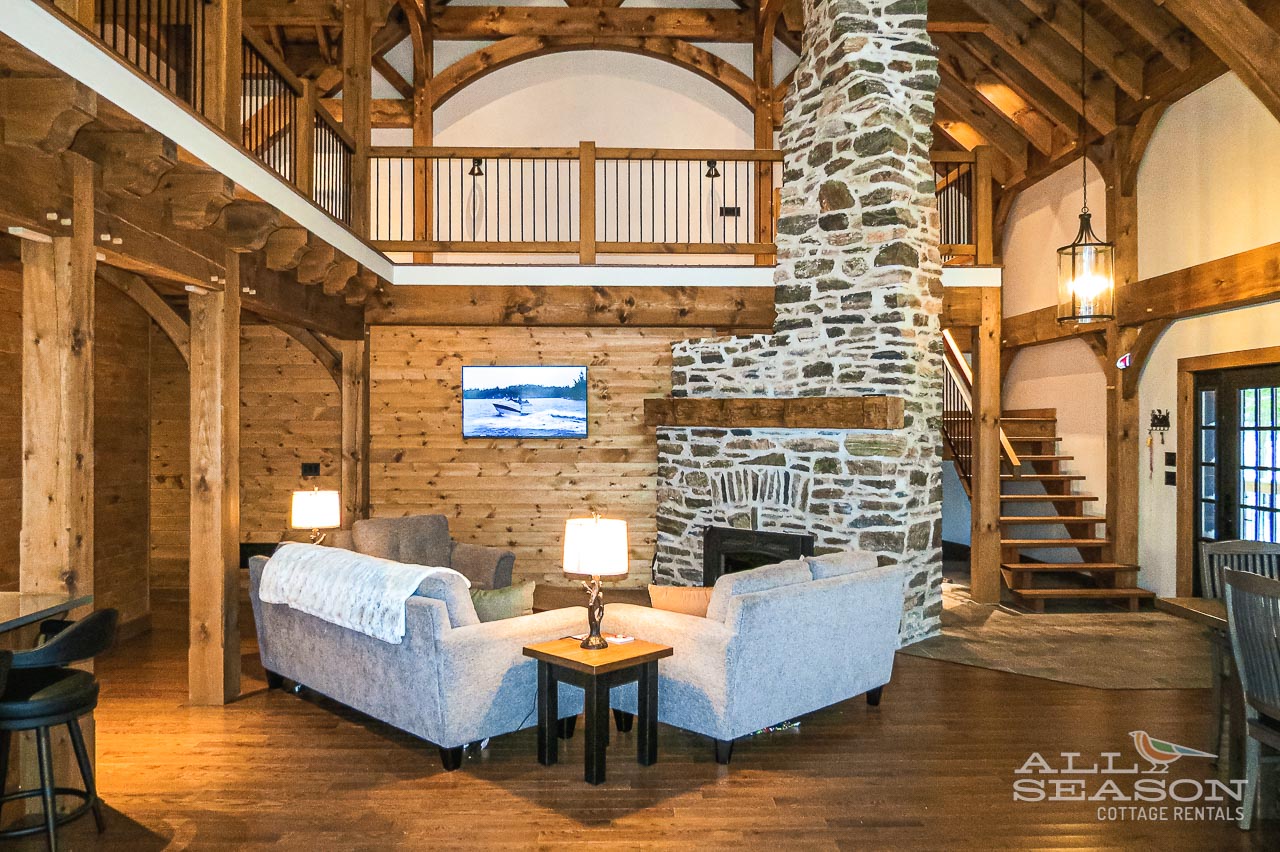 Relax in your stunning timber-frame retreat featuring soaring ceilings, exposed wooden beams, and a magnificent stone fireplace that creates the perfect mountain getaway atmosphere.