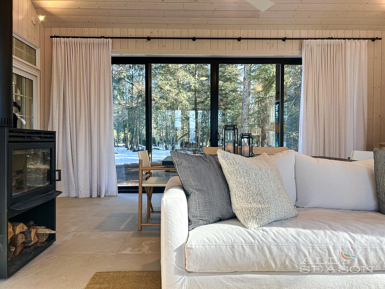 Curl up on your plush sofa by the crackling fireplace, watching snow fall through panoramic windows in this cozy winter retreat.