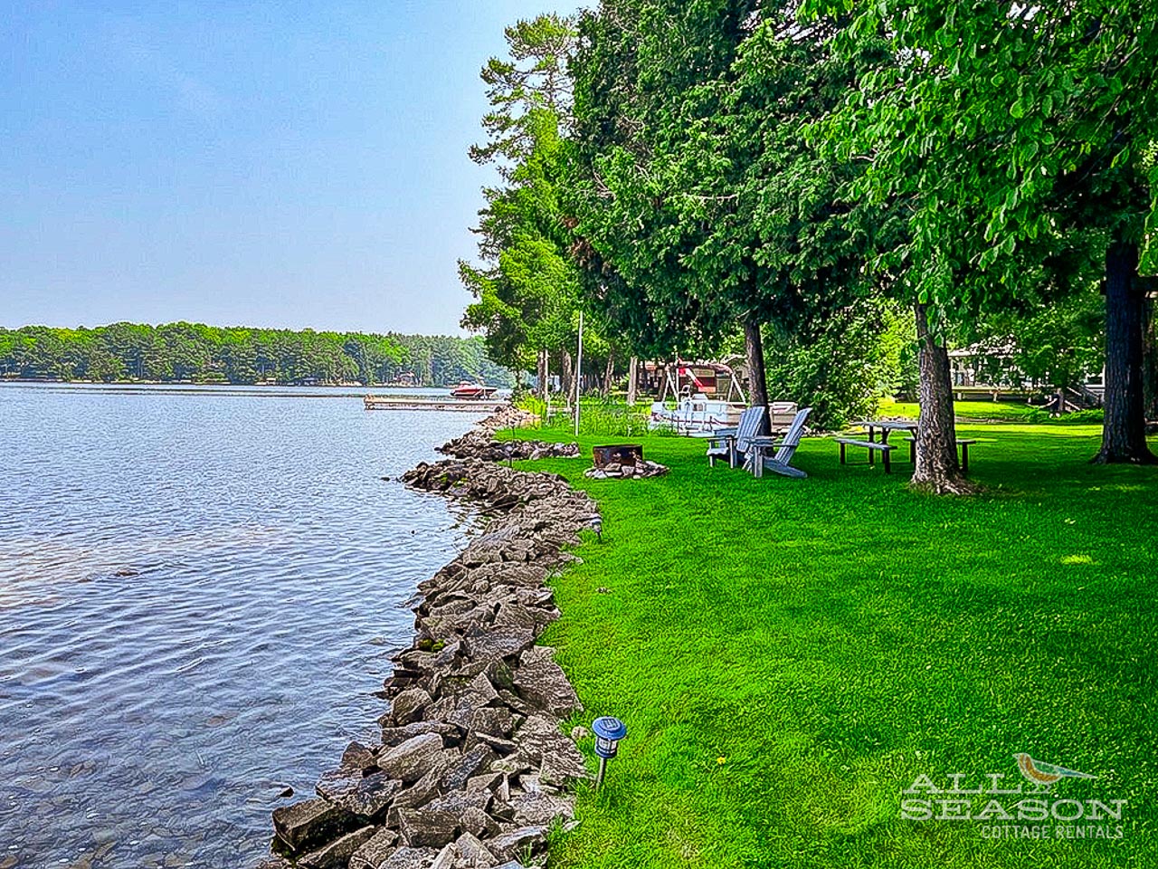 Waterfront property features direct lake access with private lawn stretching to the shoreline and mature trees providing natural shade.