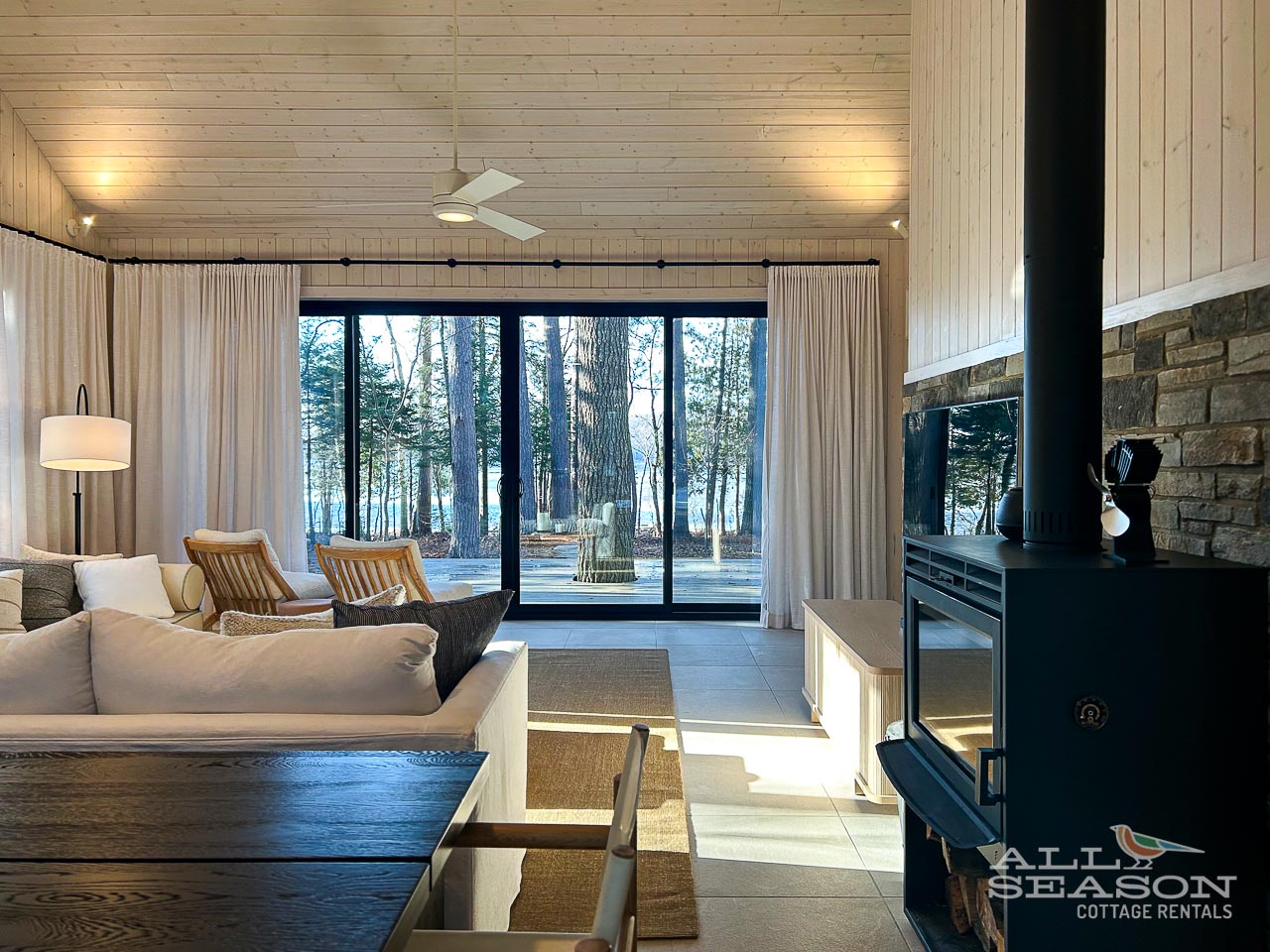 Unwind in this modern living space where warm wood meets contemporary comfort, with forest views through floor-to-ceiling windows.