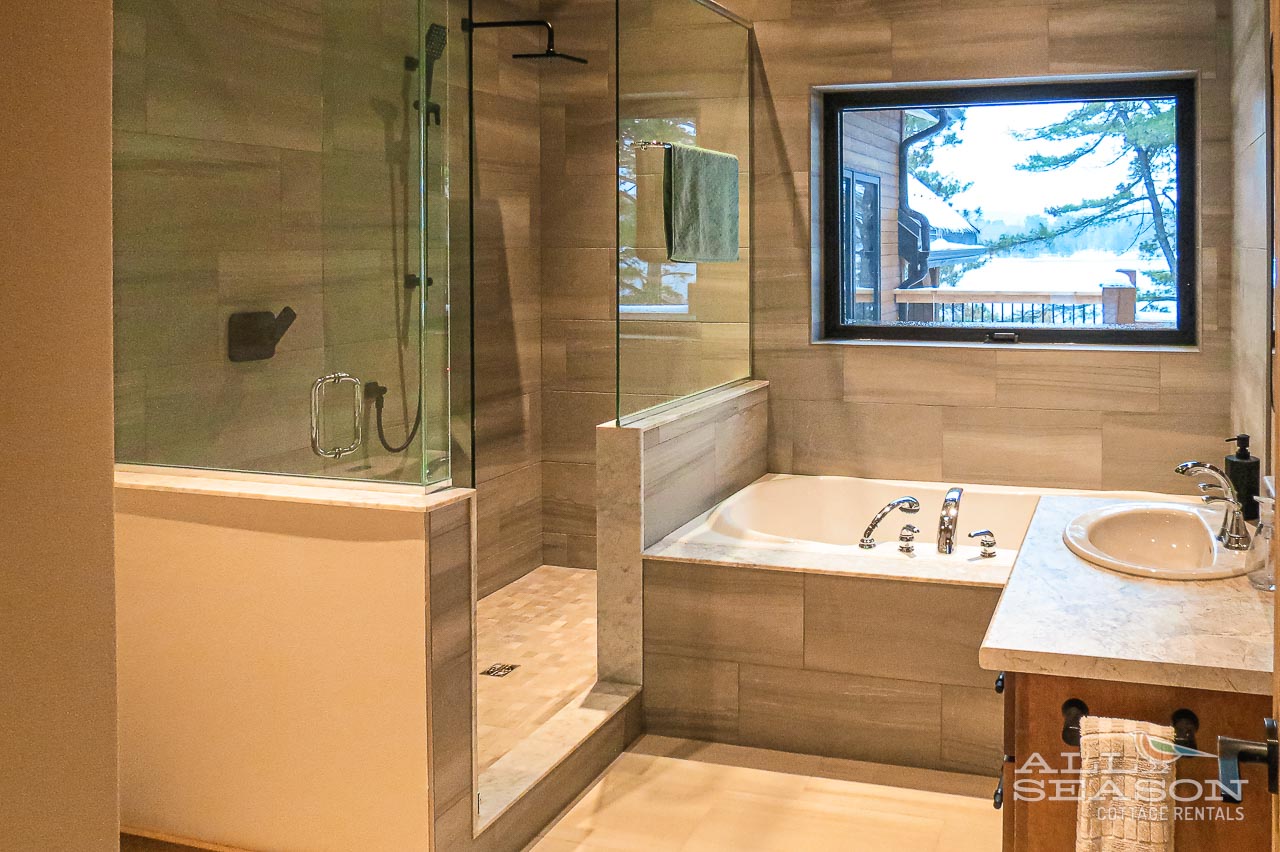 Unwind in your luxurious bathroom sanctuary with a deep soaking tub, rainfall shower, and serene nature views through the picture window.