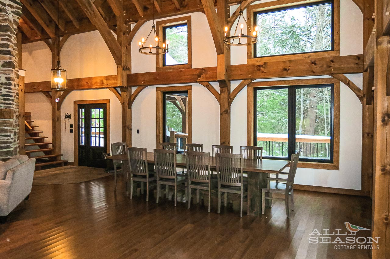 Gather around your rustic dining table beneath soaring timber beams and warm chandeliers, creating unforgettable memories with stunning forest views.