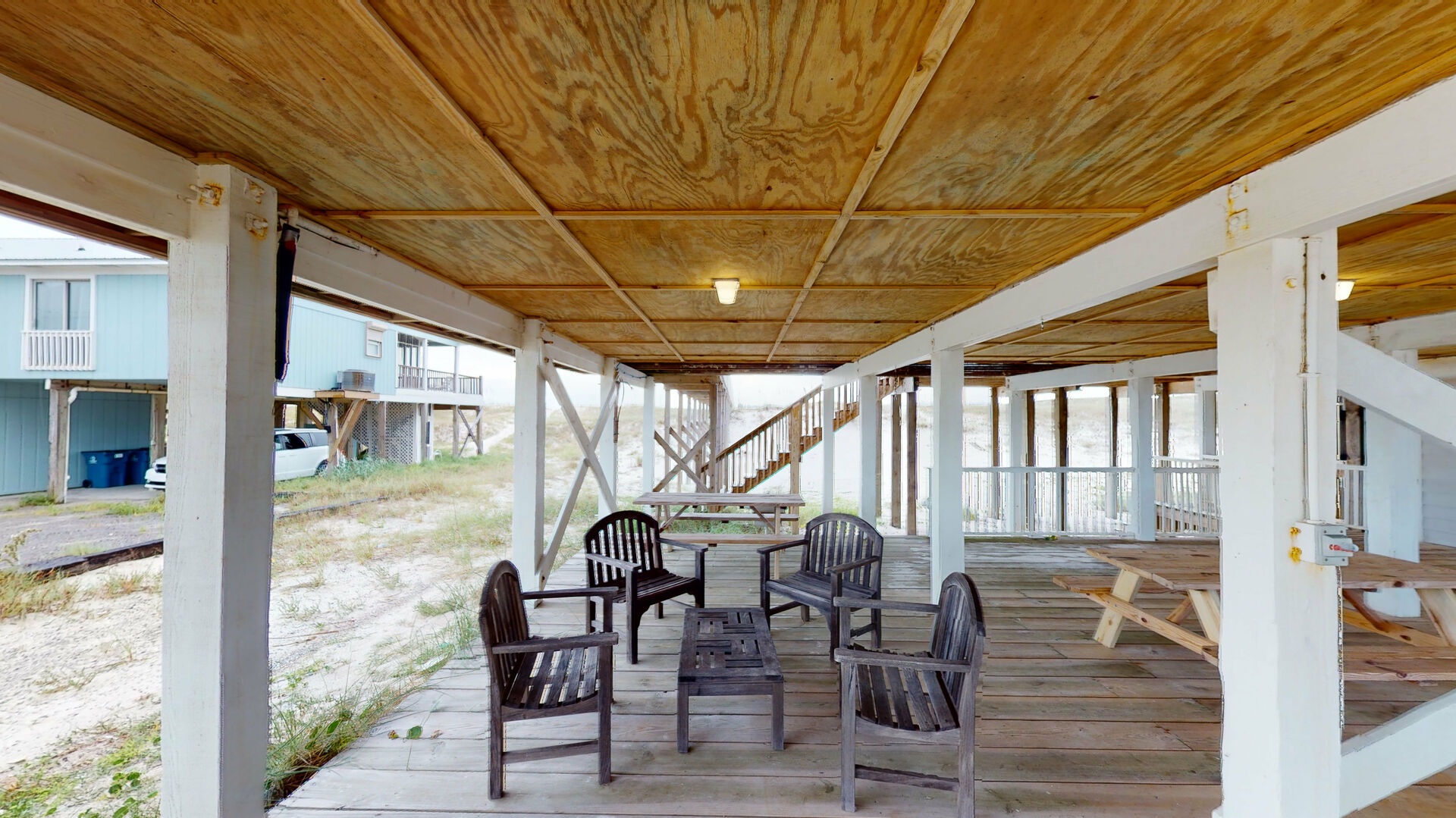 Shady area under the home with a picnic table, seating and places to hang hammocks