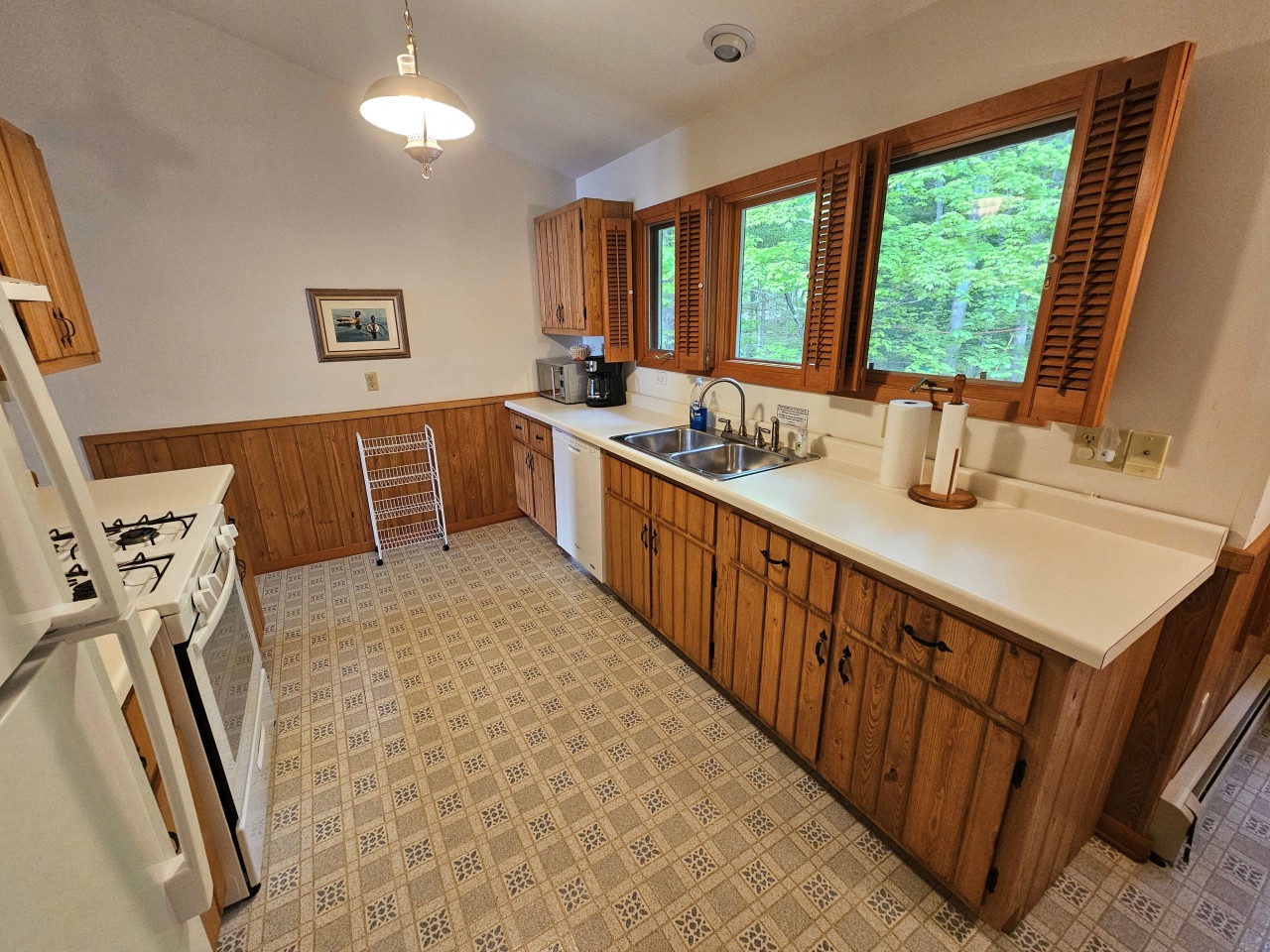 Your fully-equipped kitchen features warm wood cabinets and garden views through beautiful wooden shutters, perfect for preparing meals in comfort.