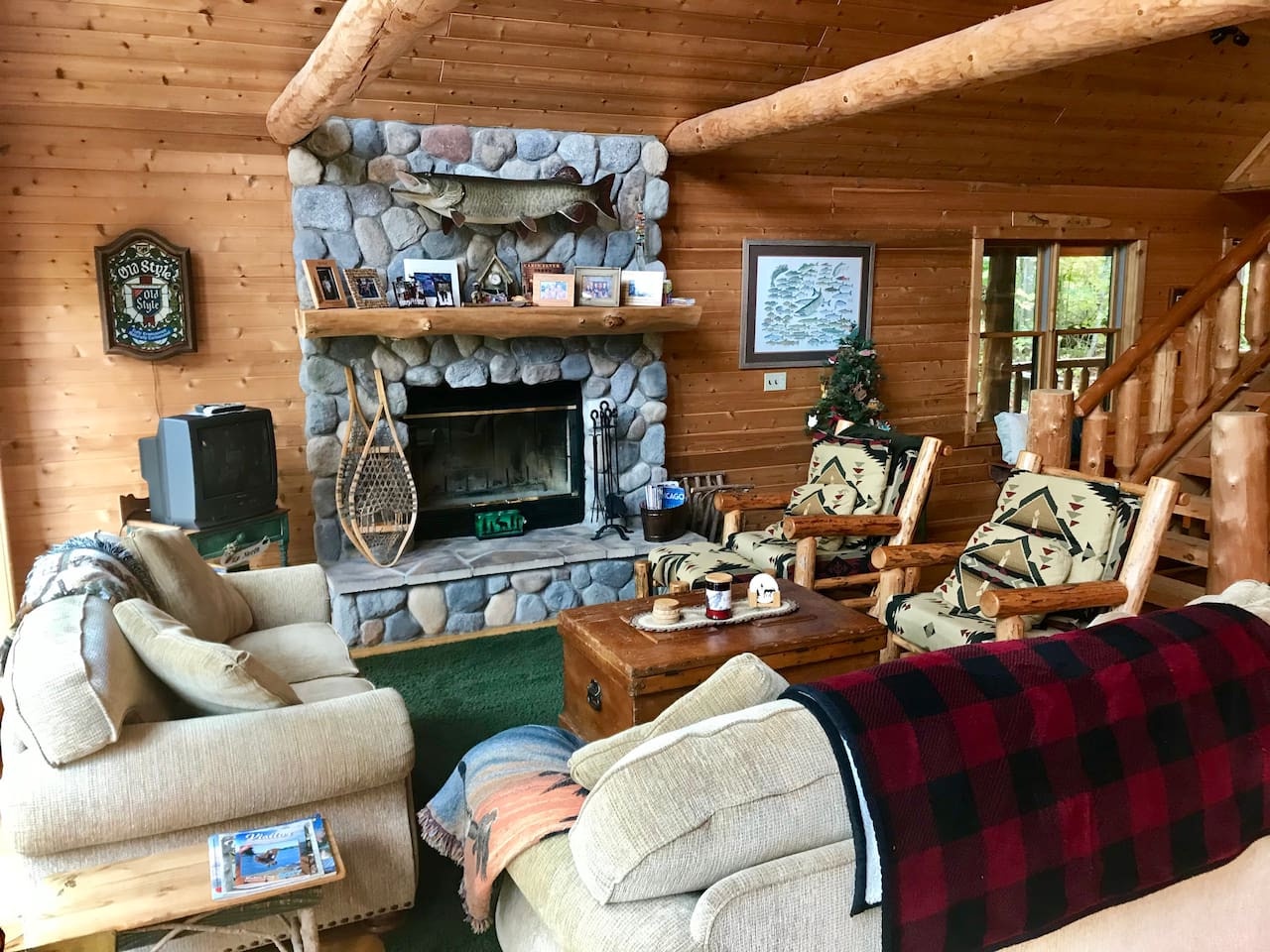 Cozy up in your rustic living room by the stone fireplace, where log cabin charm meets comfortable seating for perfect evenings.