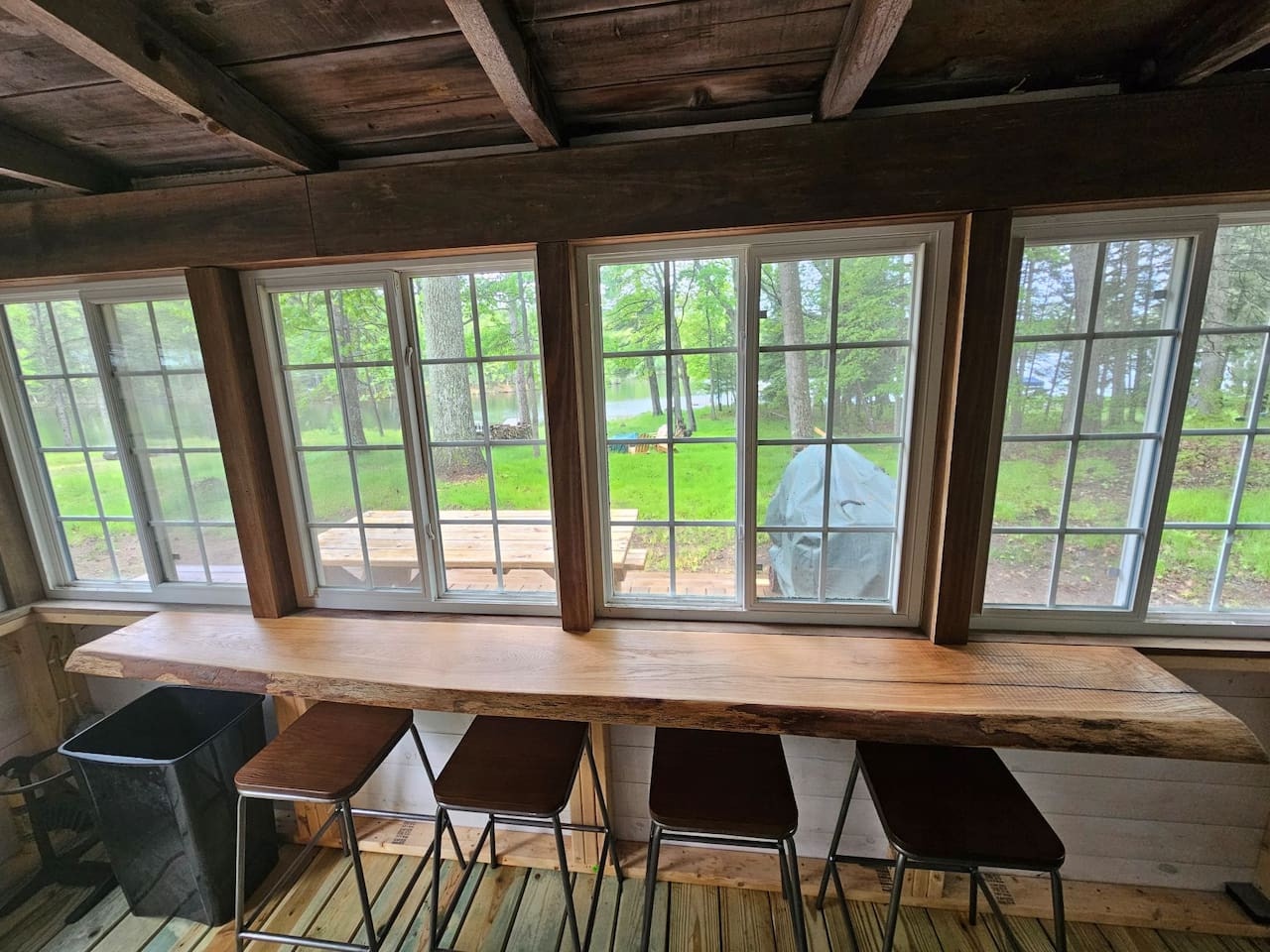 Your rustic dining space features a stunning live-edge wooden table where you can savor meals while gazing at peaceful garden views through expansive windows.
