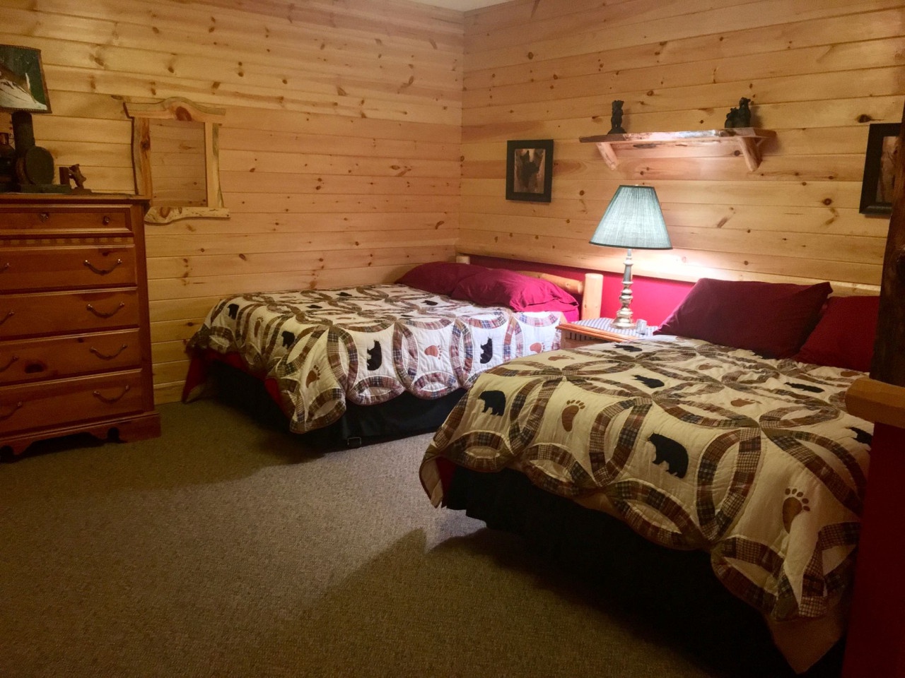 Settle into your cozy log cabin bedroom with twin beds featuring rustic wilderness quilts, warm wood walls, and charming furnishings.