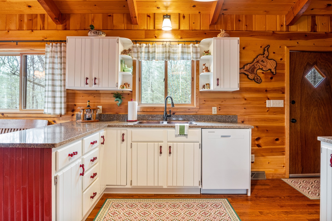 Your charming cabin kitchen combines rustic wood warmth with modern conveniences, featuring granite counters and forest views.