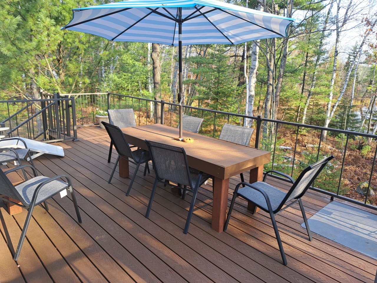 Your private forest retreat awaits with dining space for six under a protective umbrella, surrounded by towering trees and nature's tranquil embrace.