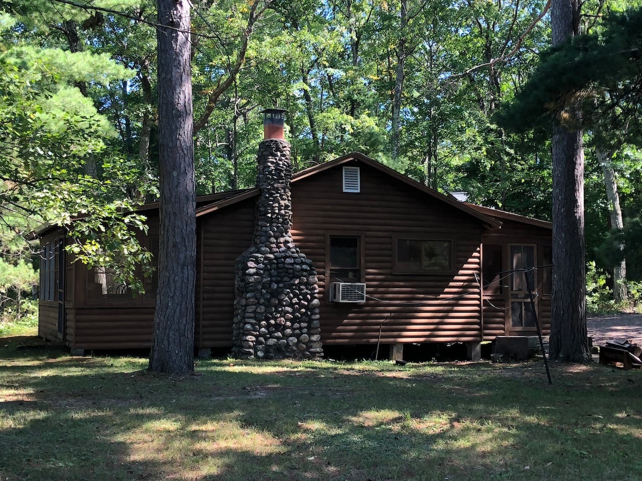 Rustic log cabin nestled among towering trees featuring a stunning stone chimney and peaceful woodland surroundings for your perfect forest retreat.