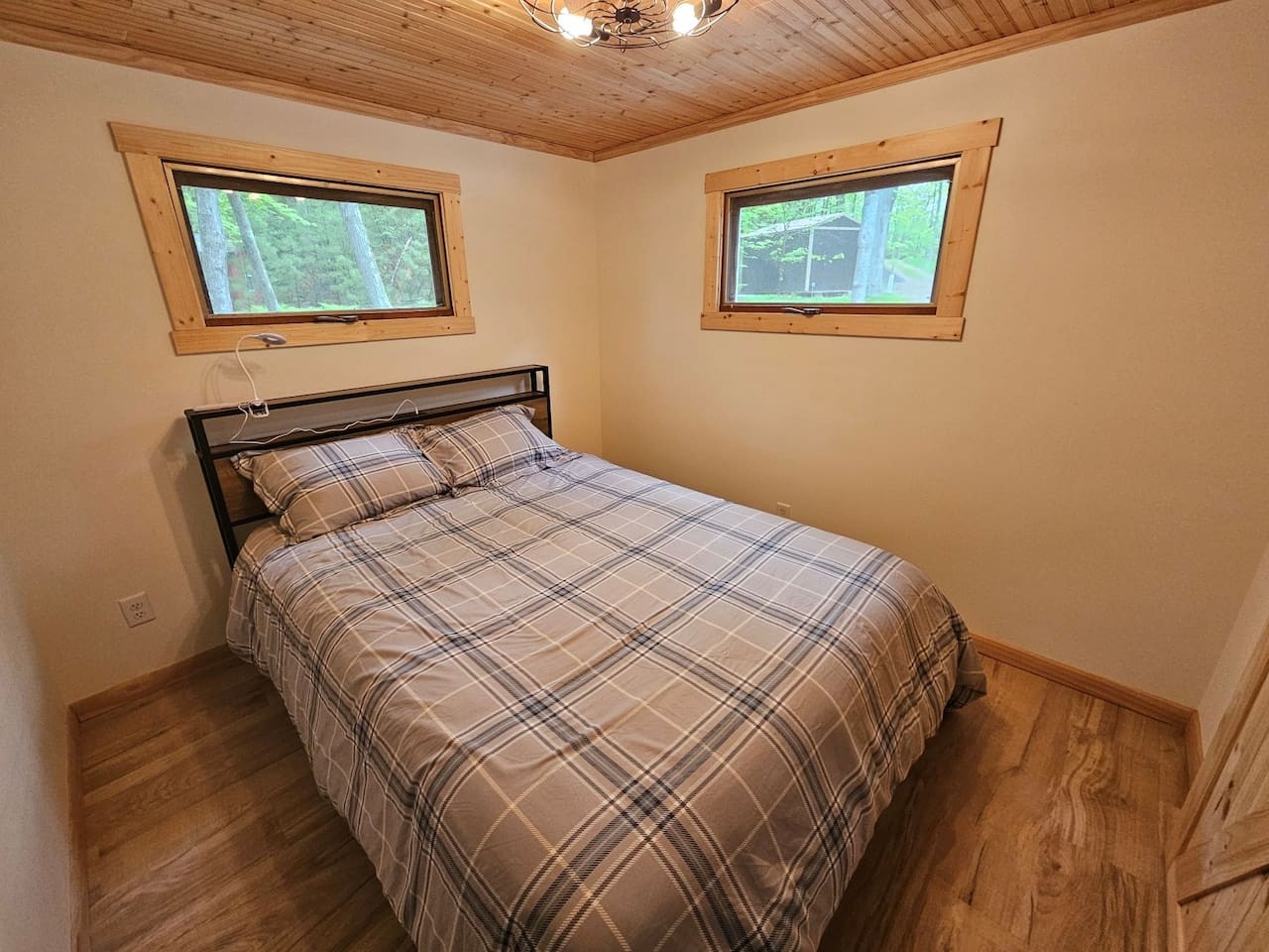 Wake up to forest views from your cozy bedroom, where rustic wood ceiling meets modern comfort for perfect retreat vibes.
