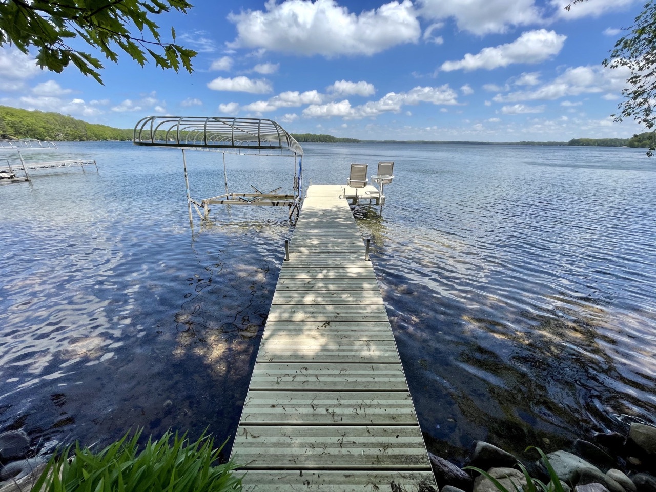 Private lake dock with boat lift and seating area surrounded by pristine waters and forested shoreline.